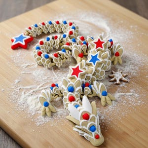 May include: A beige dragon-shaped sculpture with red and blue star accents. The dragon is decorated with red and blue dots and stars. The sculpture is on a wooden cutting board with white powder.
