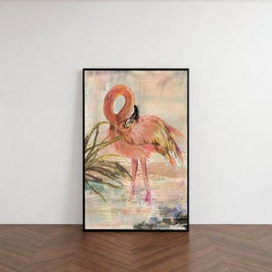 以下が含まれることがあります： 熱帯を背景にしたフラミンゴのフレーム入りアートプリント。アートワークは、頭を傾けたピンク色のフラミンゴを、落ち着いた色と葉の背景に描いています。フレームは黒です。