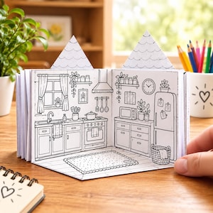 Puede incluir: Un libro desplegable con una ilustración en blanco y negro de un interior de cocina. La escena incluye una estufa, fregadero, refrigerador, gabinetes y una alfombra. Dos secciones de techo triangulares sobresalen de la parte superior.