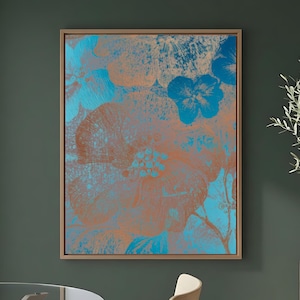 Op de afbeelding: Een ingelijste bloemenkunstprint met grote, abstracte bloemen in tinten turquoise en koper tegen een gedempte achtergrond. Het kunstwerk wordt gepresenteerd in een natuurlijke houten lijst, wat een warme uitstraling geeft.