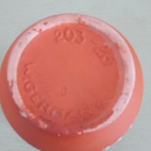 May include: The base of a terracotta pot with the text "203-28" and "Weber" in a white glaze.