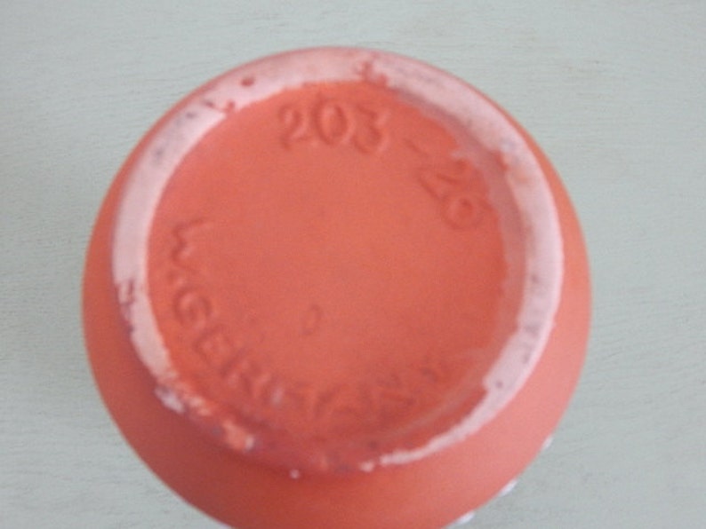 May include: The base of a terracotta pot with the text "203-28" and "Weber" in a white glaze.