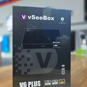 May include: A black V6 PLUS vSeeBox smart media player box. The box features the vSeeBox logo in purple and white, a graphic of the device, and icons for 4GB RAM, 64GB ROM, and 8K Ultra HD.