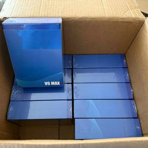 Könnte beinhalten: Ein Karton gefüllt mit mehreren blauen Boxen. Die rechteckigen Boxen tragen den Text "V6 MAX". Die Boxen sind in dem offenen Karton gestapelt.