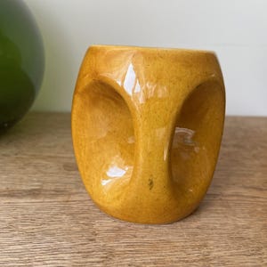 May include: A set of three ceramic mugs with a speckled, matte finish. The mugs are in shades of cream, light gray, and dark gray. Each mug has a simple, minimalist design and a rounded handle. Perfect for coffee or tea.