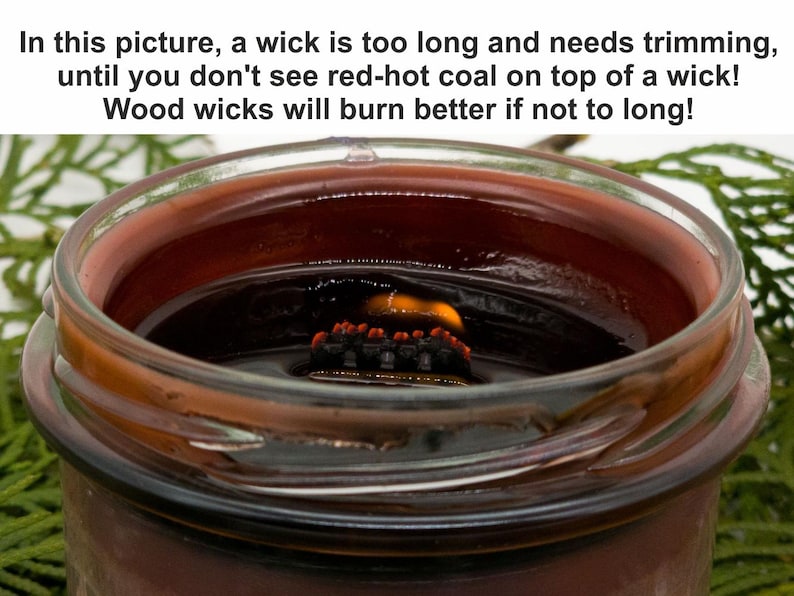 May include: A close-up of a candle in a clear glass jar. The candle has a long, charred wooden wick with red-hot coal on top. The candle wax is a dark reddish-brown color. The text in the image says the wick is too long and needs trimming.