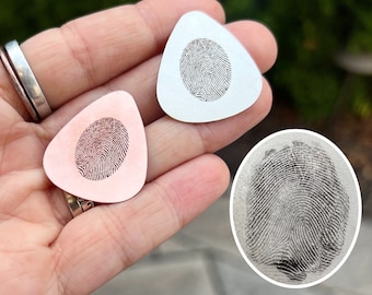 May include: Two guitar picks with a fingerprint design. One pick is silver and the other is pink.