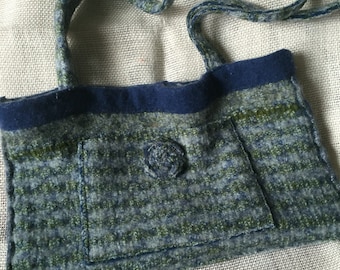 May include: A blue and green striped fabric tote bag with a single button closure and a long strap. The bag is made from recycled materials.