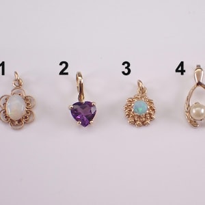 May include: Five gold pendants numbered one through five. Pendant one is an oval opal in a filigree setting. Two is a heart-shaped amethyst. Three is a round opal with a textured border. Four is a wishbone shape with a pearl. Five is a pearl drop.