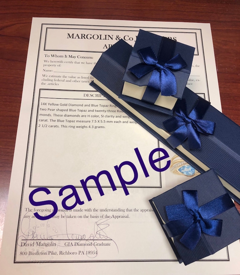 May include: A close-up of a blue velvet jewelry box with a white satin interior. The box is tied with a blue ribbon and bow. The box contains a 14K yellow gold ring with a blue topaz and diamonds. The ring weighs 4.3 grams. The appraisal document is visible in the background.