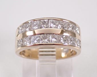 Op de afbeelding: Een gouden ring met twee rijen vierkant geslepen edelstenen. De ring heeft een gepolijste gouden band en wordt op een transparante standaard gepresenteerd. De edelstenen zijn helder en reflecteren licht.
