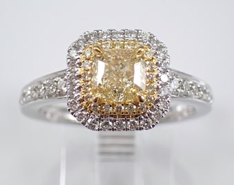 May include: A gold and white diamond engagement ring with a square-shaped center stone. The center stone is surrounded by a double halo of smaller diamonds.