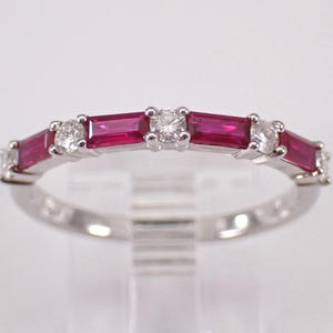 May include: A silver ring with alternating rectangular rubies and round diamonds. The rubies are a deep red, and the diamonds sparkle. The ring is set in a polished silver band, creating a classic and elegant design.