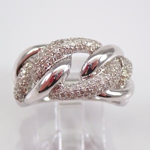 Könnte beinhalten: Ein silberfarbener Ring mit Kettenglied-Design. Das Band wechselt zwischen glatten, polierten Metallgliedern und texturierten Gliedern, die mit zahlreichen kleinen, klaren, funkelnden Steinen besetzt sind, welche das Licht reflektieren.