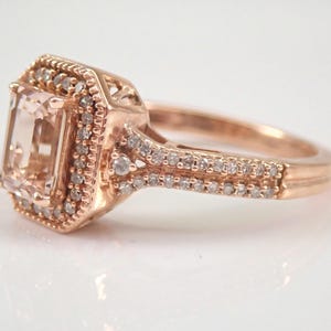 May include: A rose gold engagement ring with a large, square-cut, light pink gemstone surrounded by a halo of smaller diamonds. The band is also set with smaller diamonds.