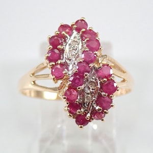 May include: A gold ring with a cluster of red rubies and small diamonds set in a leaf-like design.