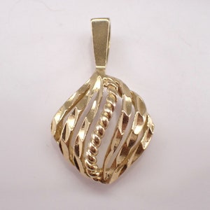 Puede incluir: Un colgante de oro con un diseño geométrico. El colgante está hecho de múltiples hebras de oro que se retuercen y tejen juntas para crear un patrón único e intrincado.