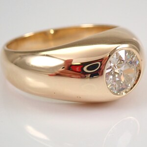 May include: A gold ring with a large, round, bezel-set diamond.