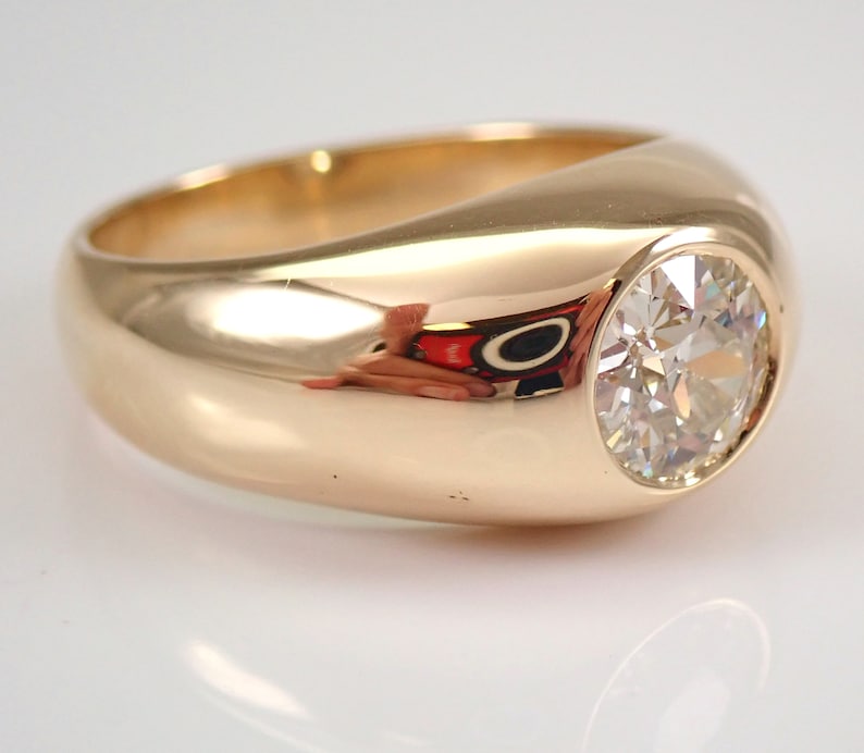 May include: A gold ring with a large, round, bezel-set diamond.