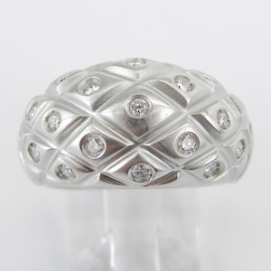 Könnte beinhalten: Ein silberner Ring mit einem strukturierten Kuppeldesign und kleinen Diamanten, die in die Oberfläche eingefasst sind.