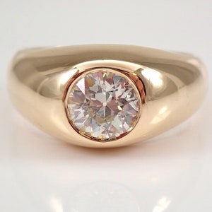 May include: A gold ring with a large, round, clear diamond set in the center. The ring has a smooth, rounded band.