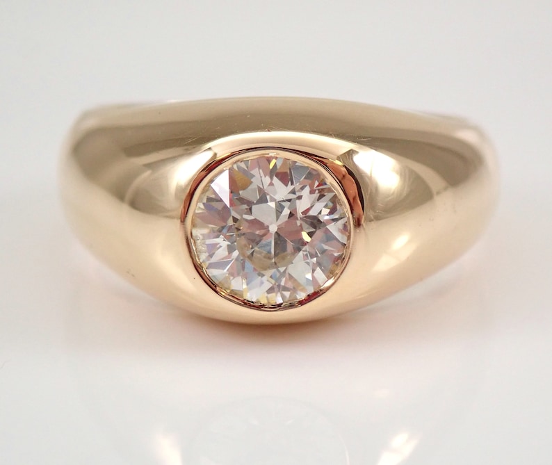May include: A gold ring with a large, round, clear diamond set in the center. The ring has a smooth, rounded band.