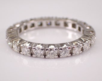 May include: A silver eternity band with a row of round, clear diamonds.
