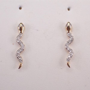 May include: A pair of gold snake earrings with clear cubic zirconia stones.