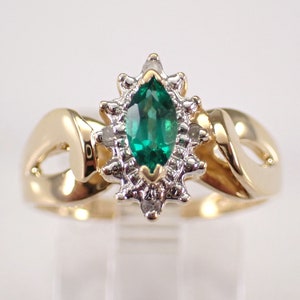 May include: A gold ring with a marquise-shaped green emerald gemstone surrounded by a halo of small white diamonds.