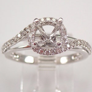 May include: A white gold engagement ring with a round halo setting and a split shank. The halo and shank are accented with small diamonds.