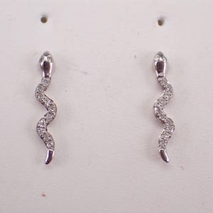 Op de afbeelding: Een paar zilveren slangenoorbellen met heldere zirkonia-stenen.