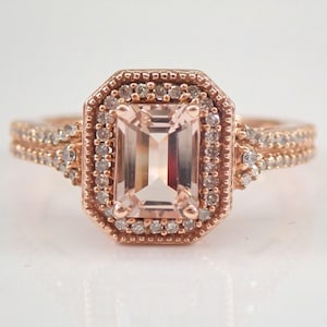May include: A rose gold engagement ring with a large, rectangular morganite center stone surrounded by a halo of smaller diamonds. The band is also set with diamonds.