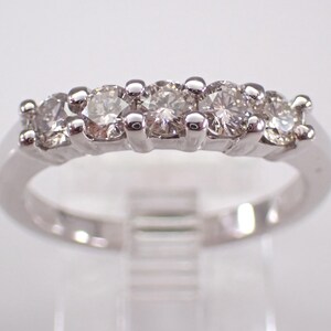 Könnte beinhalten: Ein Weißgoldring mit fünf runden Diamanten in einer Reihe. Die Diamanten sind klar und funkelnd, und der Ring hat eine polierte Oberfläche. Der Ring ist ein klassisches Design, geeignet für verschiedene Anlässe.