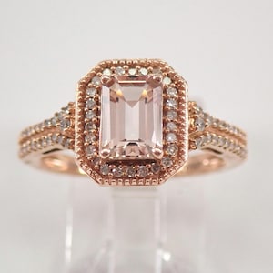May include: A rose gold engagement ring with a large, rectangular, light pink morganite gemstone surrounded by a halo of smaller diamonds. The band is also set with smaller diamonds.