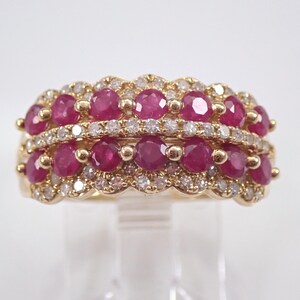 May include: A gold ring featuring three rows of vibrant red rubies and sparkling diamonds. The ring's design showcases a scalloped edge, with the gemstones set closely together, creating a luxurious and eye-catching piece of jewelry.