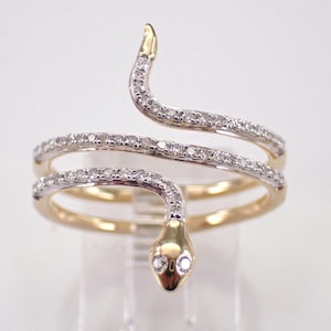 May include: A gold and silver snake ring with a diamond-encrusted design. The ring is made of two bands that wrap around the finger and are connected by a snake head.