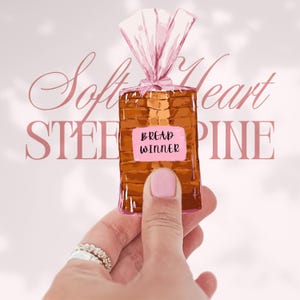 May include: Illustration of a loaf of bread in a clear plastic bag, held by a hand with a pink painted nail. The bread has a pink label that says "Bread Winner". The background has the words "Soft Heart Stee Pine" in a pink script.