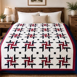 Könnte beinhalten: Eine Steppdecke mit einem sich wiederholenden geometrischen Sternmuster in Marineblau, Weiß und Dunkelrot. Das zentrale Design besteht aus ineinandergreifenden Formen auf weißem Grund, umrahmt von einer roten Bordüre und einem marineblauen Rand.