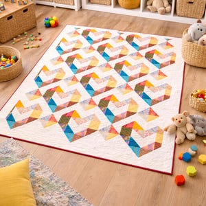 May include: A vibrant geometric quilt featuring a heart design in blue, yellow, orange, and green hues. The quilt has a white base and a red border. It's placed on a wooden floor, likely in a child's playroom.