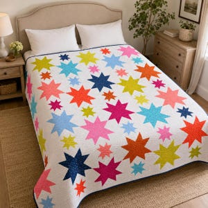 Puede incluir: Una colcha blanca con un patrón repetitivo de estrellas de ocho puntas multicolores en tonos rosa neón, naranja brillante, verde lima, azul cielo y azul marino. La tela presenta una textura sutil de puntos finos en todo el diseño.