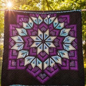 Könnte beinhalten: Ein geometrischer Quilt mit einem Sternmuster. Der Quilt zeigt einen zentralen Stern in Weiß und Hellblau, umgeben von violetten und schwarzen geometrischen Formen. Der Quilt hängt draußen, mit Sonnenlicht, das durch die Bäume scheint.