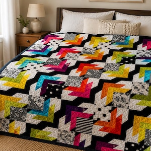 May include: A quilt featuring a geometric arrow pattern in vibrant neon colours including pink, orange, yellow, and teal, contrasted with black and white blocks in various patterns like polka dots, stripes, and floral prints, all stitched with a diamond grid.