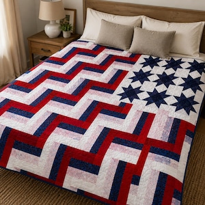 May include: A quilt featuring a red, white, and blue chevron pattern across the main body and a section of dark blue fabric with white star shapes in the upper corner. The textile design incorporates a patriotic colour scheme with geometric shapes.