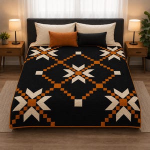 May include: A quilt featuring a black background with a repeating geometric star pattern in white and orange. The fabric has a subtle scalloped quilted texture throughout. The design includes a central star motif surrounded by smaller stars.