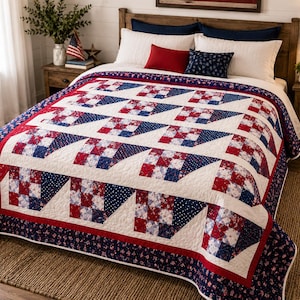 May include: A red, white, and blue quilt with a geometric pattern on a bed. The quilt features a patchwork design with squares and triangles. The bed is made up with white pillows and a wooden headboard. The quilt is approximately 90 inches by 90 inches.