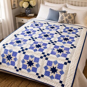 May include: A white and blue quilt with a star pattern is displayed on a bed. The quilt features a repeating design of blue stars and squares against a white background. The quilt is bordered with a dark blue trim.