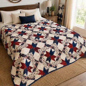Puede incluir: Una colcha con un patrón repetitivo de estrellas en rojo, blanco y azul. El diseño incorpora telas con pequeños estampados de banderas estadounidenses y motivos de estrellas azul marino sobre un fondo crema con textura acolchada.