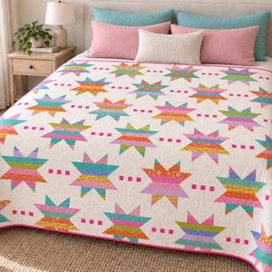 May include: A white quilt featuring a repeating pattern of multi-colored, striped star shapes in shades of pink, orange, yellow, green, and blue. The quilt is finished with a bright pink border and small pink square accents between the stars.