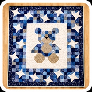 May include: A handmade quilt featuring a patchwork teddy bear design in shades of blue and tan. The bear is centered on a white background, surrounded by a border of blue squares and white stars. The quilt is approximately 40 inches square.