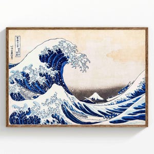 Könnte beinhalten: Ein gerahmter Druck von Hokusais "Die große Welle vor Kanagawa". Das Kunstwerk zeigt eine große Meereswelle mit weißer Gischt, die sich über einem dunkelblauen Meer kräuselt. Kleine Boote sind sichtbar, und der Berg Fuji ist im Hintergrund. Der Druck ist in einem Holzrahmen.